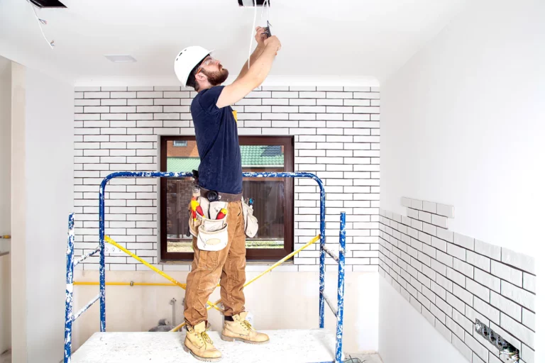 A worker on scaffolding dismantles wiring on the ceiling