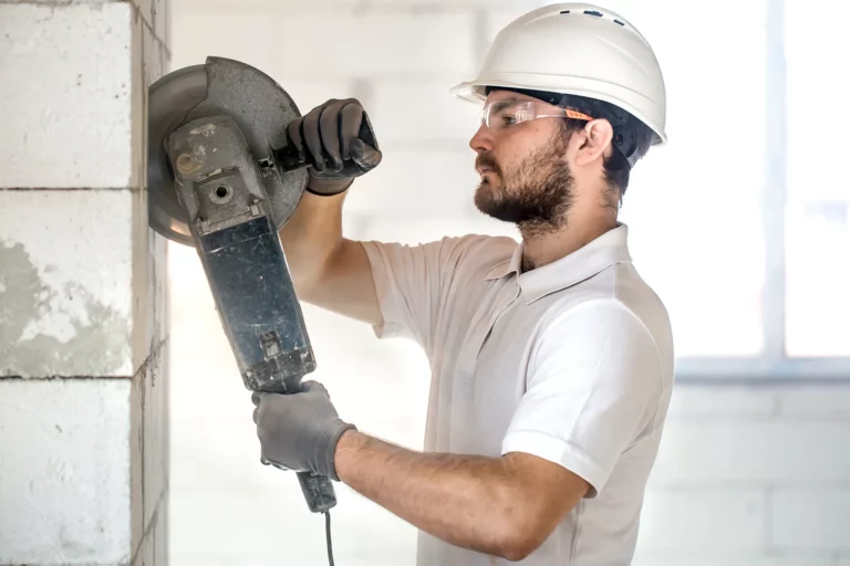 A worker in a white helmet is engaged in dismantling