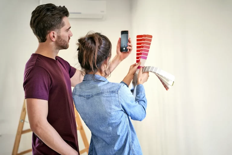 An interior designer and a client are holding a color palette and discussing what color to paint the walls.