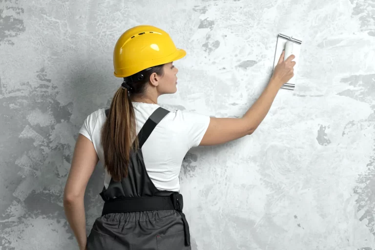 girl in a hard hat plasters a wall while renovating an apartment