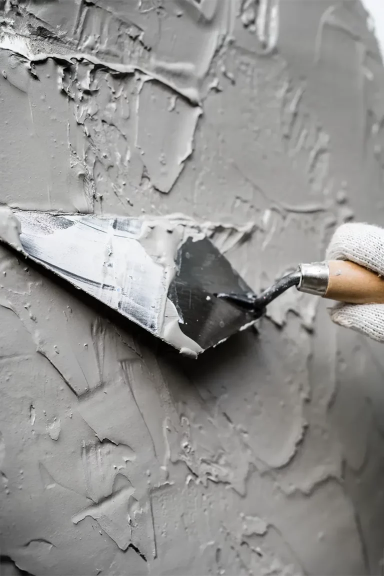 worker with spatula applying plaster to wall