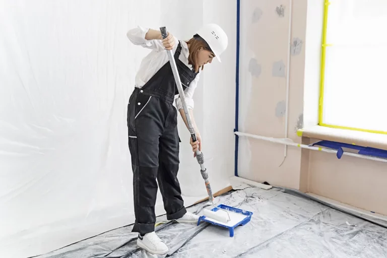 apartment renovation painting work, a girl in work clothes paints a wall