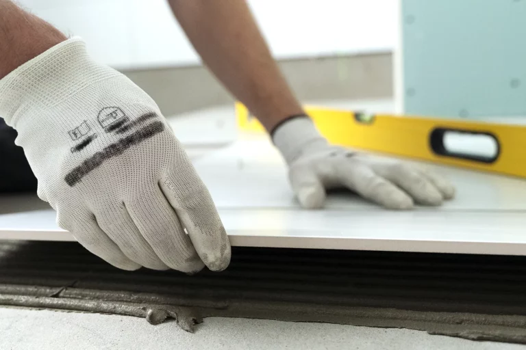 man in gloves laying tiles