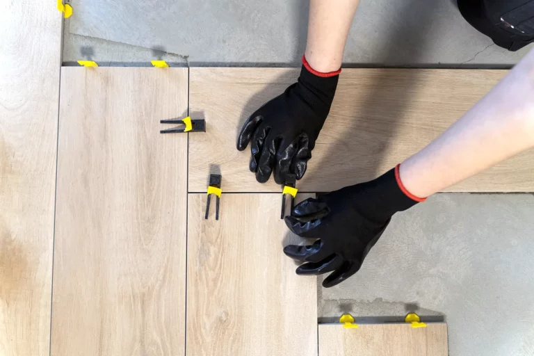 girl in black gloves lays tiles on the floor