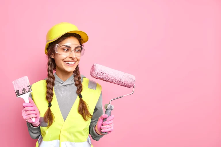 girl worker holds a roller and a brush with paint, paints the wall